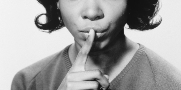 Young woman with finger on lips, (B&W), portrait
